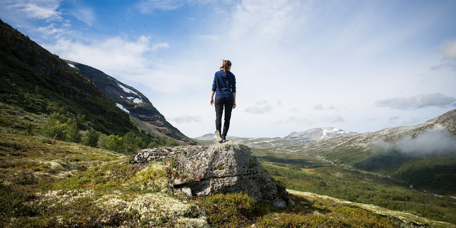 person standing on rock looking at mountain